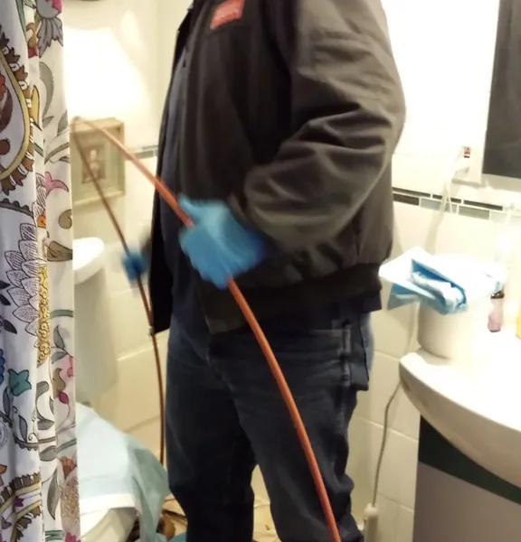 A technician operating a drain cleaning machine during an in-home service call
